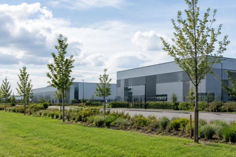 Modern industrial buildings seen beyond a planted grass verge and young trees