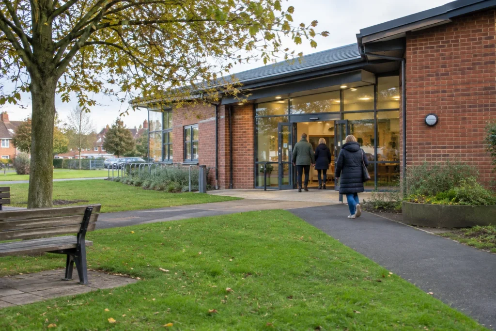 An anonymous brick community building with a glazed entrance beside a public green space
