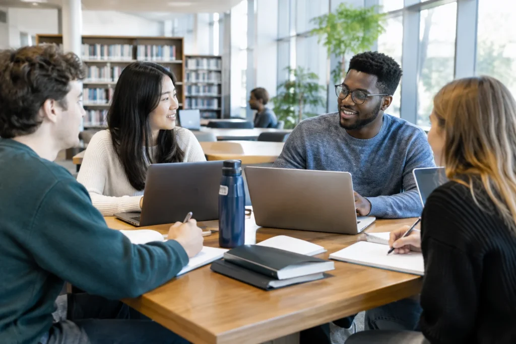 Students sharing notes around a library study table